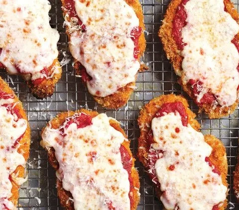 Martha Stewart chicken parmesan with bubbly melted mozzarella and fresh basil on a baking sheet