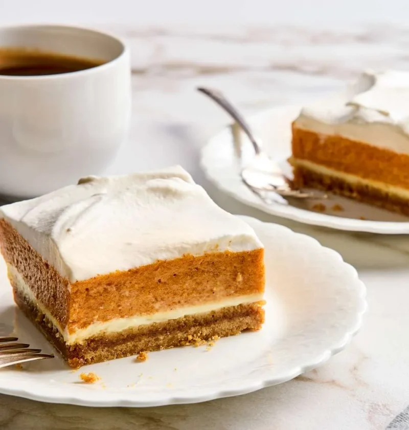 Sliced pumpkin mousse cheesecake squares with graham crust and whipped cream