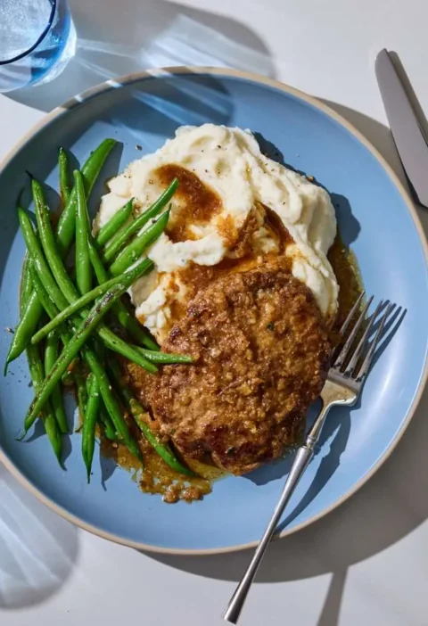 Salisbury steak patties covered in caramelized onion gravy on a plate, a Martha Stewart Salisbury Steak With Onion Gravy recipe
