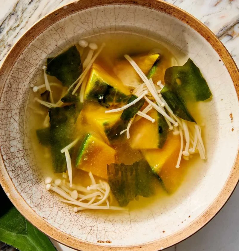 Bowl of squash and mushroom miso soup with kabocha chunks and enoki mushrooms in golden broth
