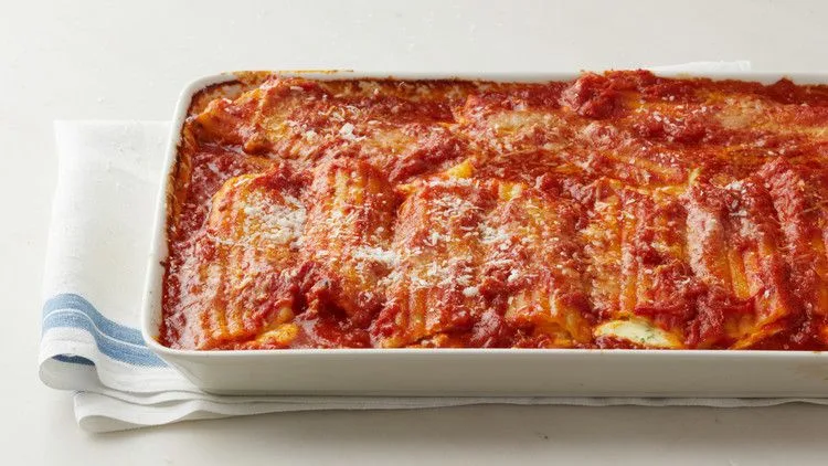 Baked manicotti shells filled with ricotta and mozzarella in marinara sauce topped with browned Parmesan