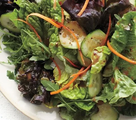 A fresh salad mix of butter lettuce, romaine, and arugula with sliced cucumber and shredded carrot drizzled with balsamic vinaigrette
