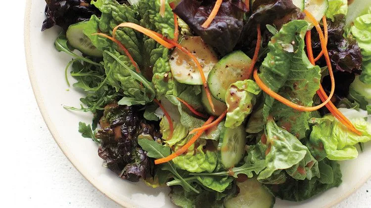 A fresh salad mix of butter lettuce, romaine, and arugula with sliced cucumber and shredded carrot drizzled with balsamic vinaigrette