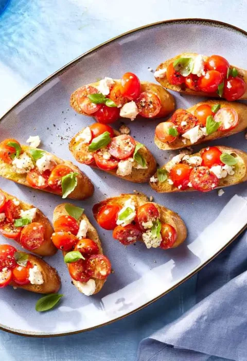 Warm bruschetta with roasted grape tomatoes, crumbled feta, and fresh basil on crispy baguette slices