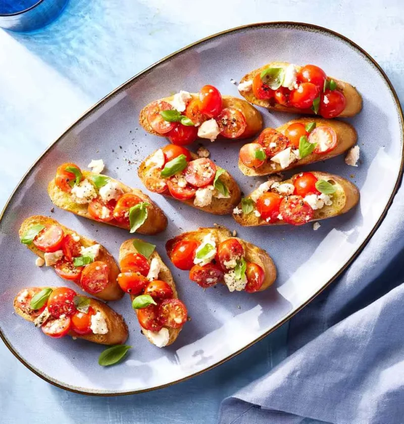 Warm bruschetta with roasted grape tomatoes, crumbled feta, and fresh basil on crispy baguette slices