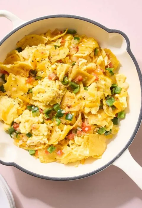 A skillet of Martha Stewart migas with crispy corn tortilla pieces folded into scrambled eggs, poblano, and melted cheddar