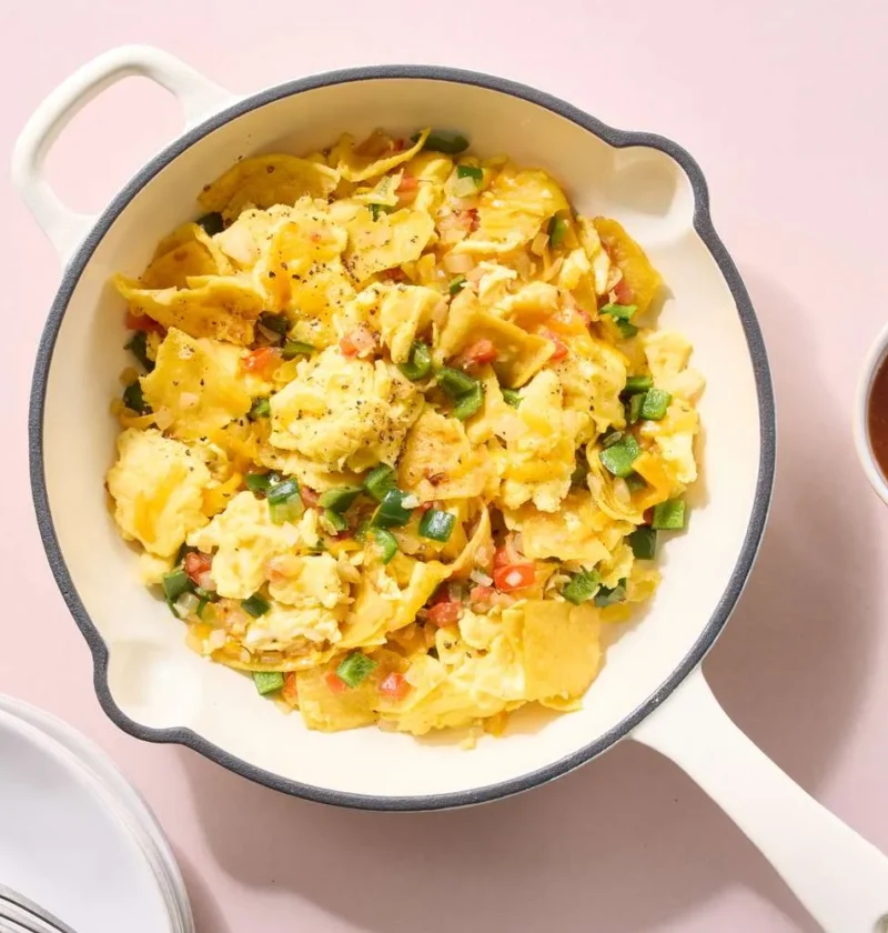 A skillet of Martha Stewart migas with crispy corn tortilla pieces folded into scrambled eggs, poblano, and melted cheddar