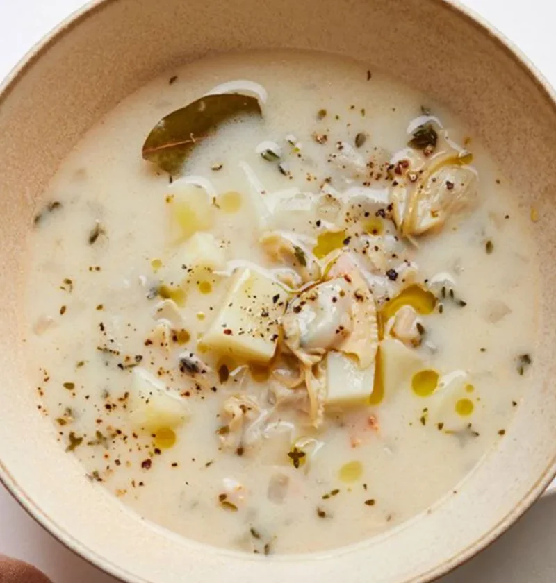 Bowl of New England clam chowder with tender clams and cubed potato in a creamy broth topped with oyster crackers