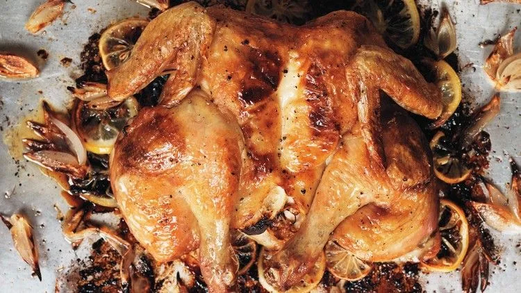 Roast spatchcocked lemon chicken on a sheet pan with golden skin, roasted lemon slices, and caramelized shallots