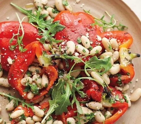 Roasted red pepper salad with white beans, anchovy dressing, and shaved Parmesan on a platter