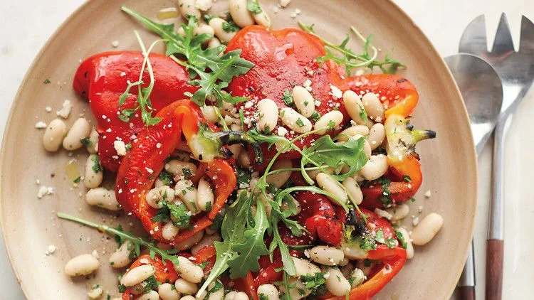 Roasted red pepper salad with white beans, anchovy dressing, and shaved Parmesan on a platter