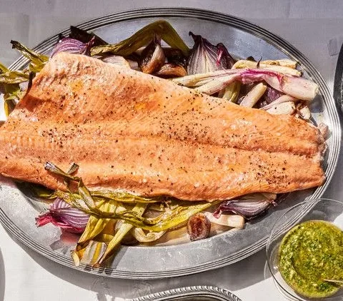 Roasted salmon fillet with bright green mint-caper pesto on a bed of caramelized shallots and scallions