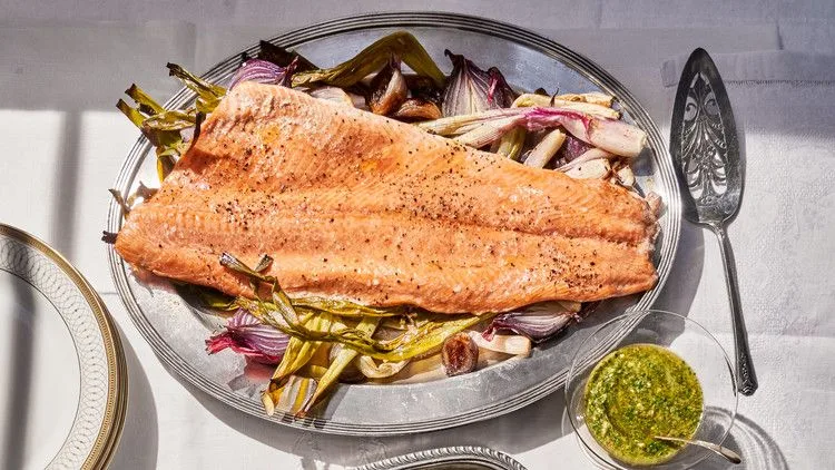 Roasted salmon fillet with bright green mint-caper pesto on a bed of caramelized shallots and scallions