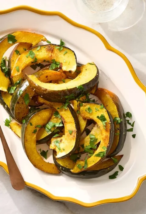 Roasted spiced acorn squash wedges with cumin and coriander on a baking sheet