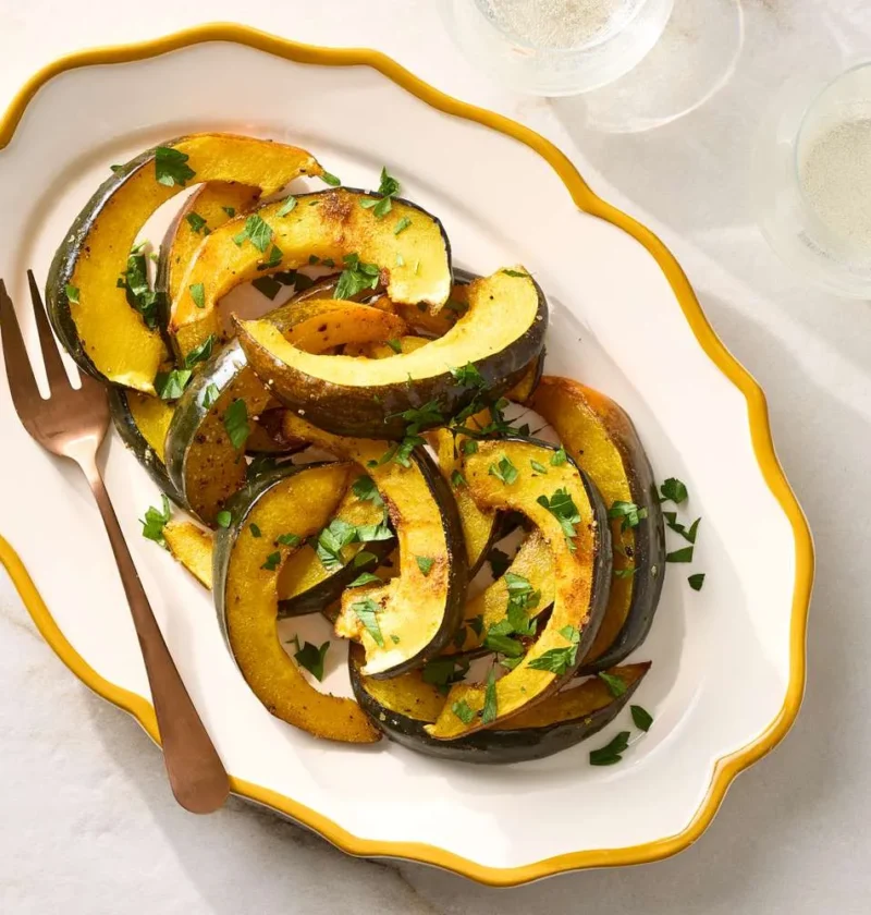 Roasted spiced acorn squash wedges with cumin and coriander on a baking sheet