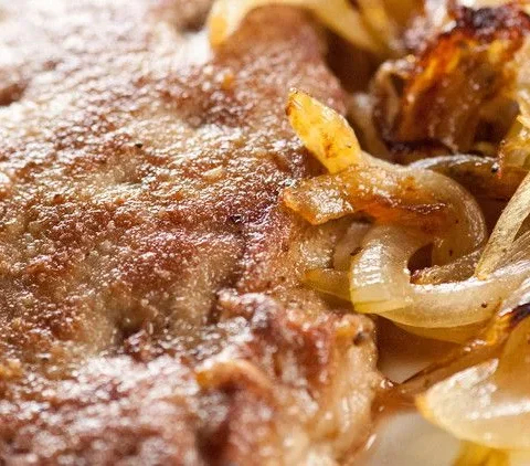 Martha Stewart sauteed calf liver browned in butter with sage and topped with caramelized onions on a white plate