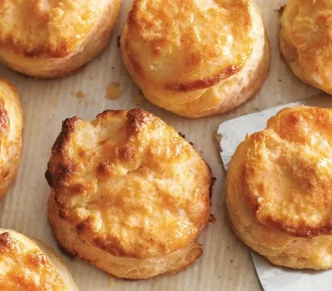 Golden flaky buttermilk biscuits fresh from the oven on a baking sheet, showing layered pull-apart texture from Martha Stewart Scott Peacock's recipe