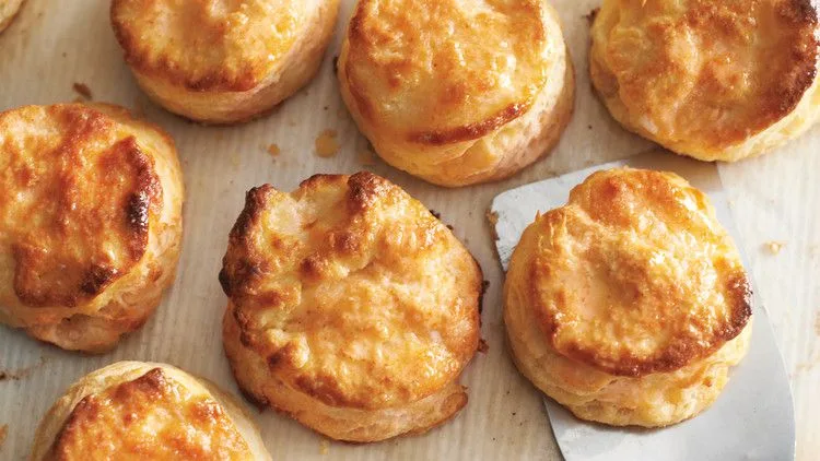 Golden flaky buttermilk biscuits fresh from the oven on a baking sheet, showing layered pull-apart texture from Martha Stewart Scott Peacock's recipe