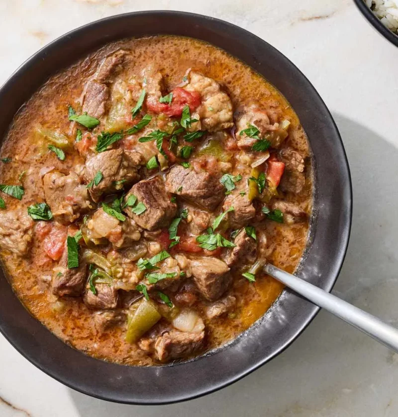 Slow-cooker carne guisada with tender beef chunks in a rich cumin-spiced tomato gravy, served in a bowl
