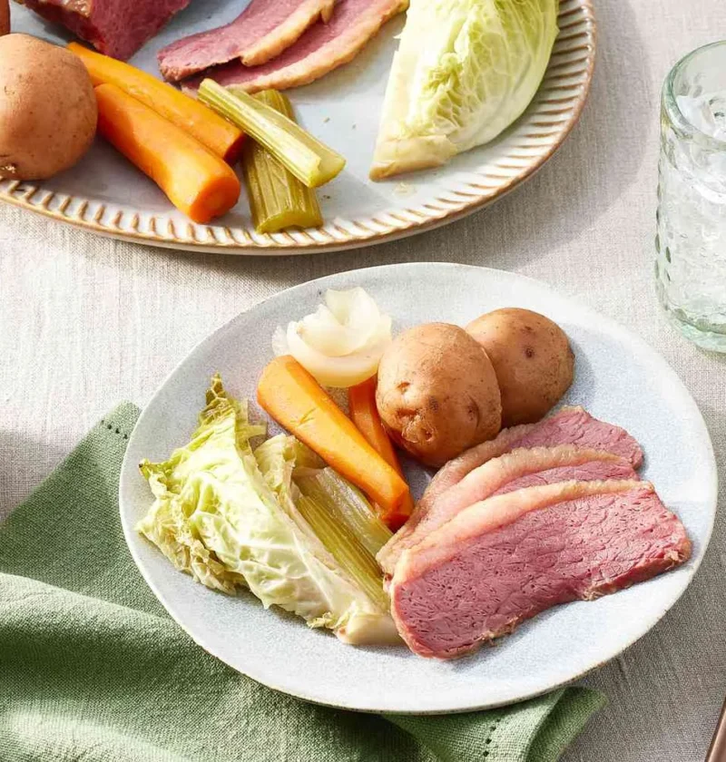 Slow-cooker corned beef and cabbage sliced against the grain on a platter with carrots, potatoes, and Savoy cabbage wedges