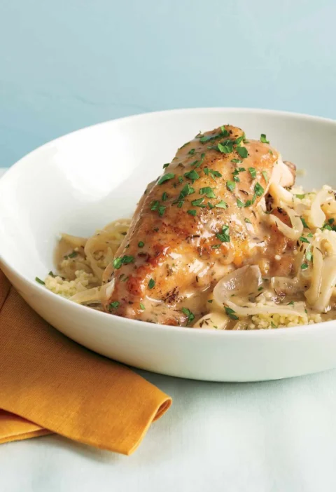 Slow-cooker garlic chicken with golden crisp skin served over fluffy couscous on a plate