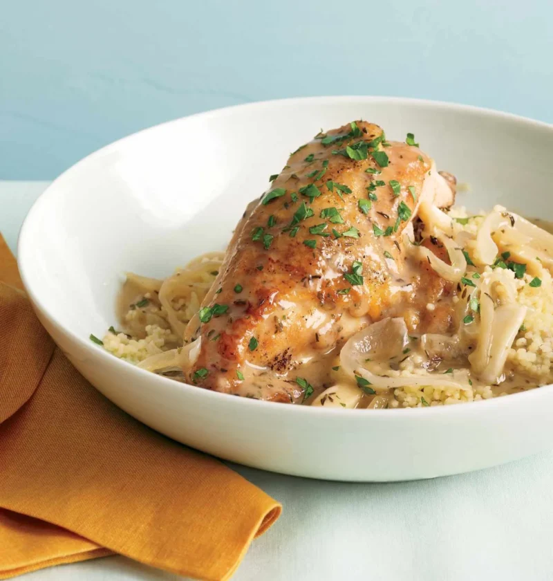 Slow-cooker garlic chicken with golden crisp skin served over fluffy couscous on a plate