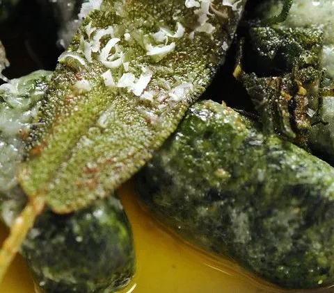 Spinach and ricotta gnudi drizzled with brown sage butter on a plate