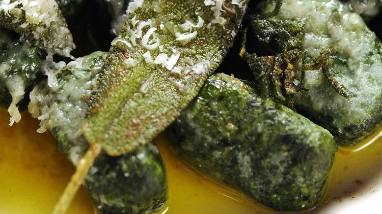 Spinach and ricotta gnudi drizzled with brown sage butter on a plate