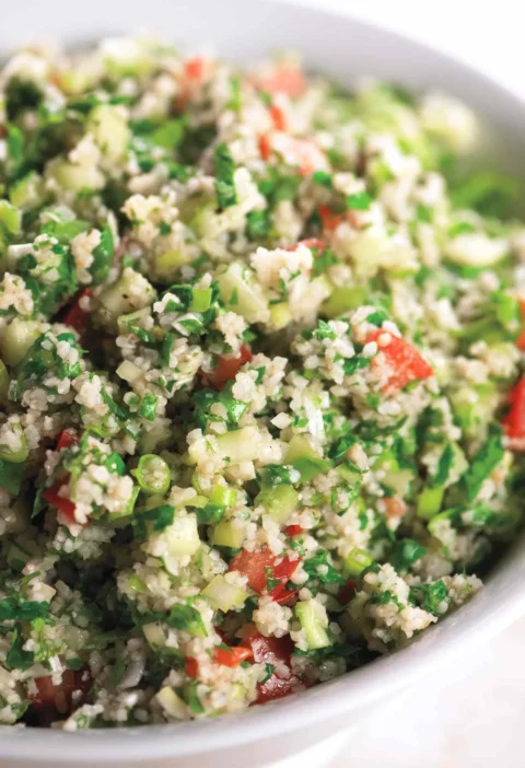 A bowl of fresh tabbouleh with bulgur, chopped parsley, mint, tomatoes, and cucumber dressed in lemon and olive oil