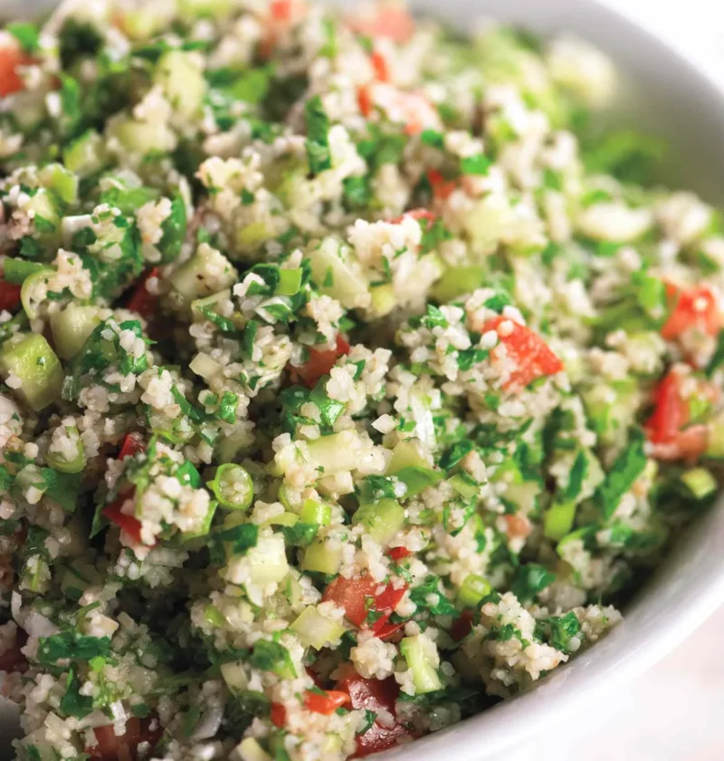 A bowl of fresh tabbouleh with bulgur, chopped parsley, mint, tomatoes, and cucumber dressed in lemon and olive oil