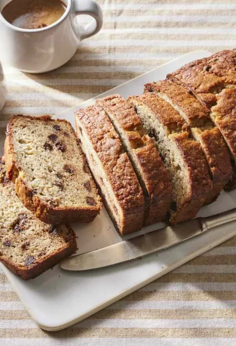 Sliced banana chocolate chip bread with melted semisweet chocolate and golden crust on a cutting board