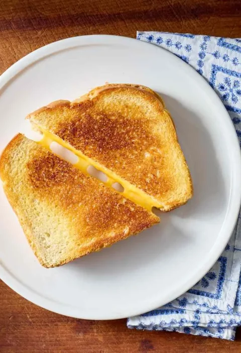 Golden grilled cheese sandwiches with melted sharp cheddar and American cheese on sourdough bread