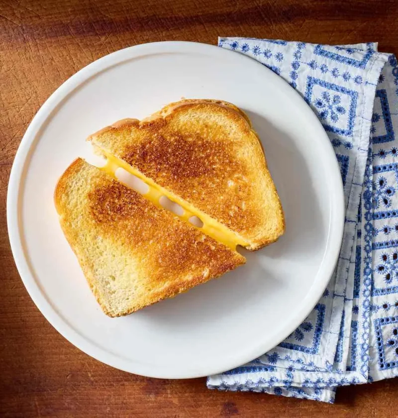 Golden grilled cheese sandwiches with melted sharp cheddar and American cheese on sourdough bread