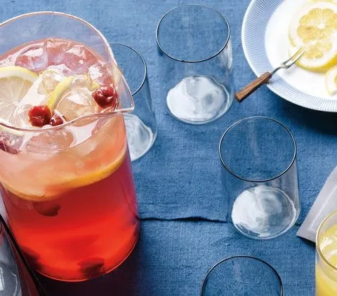 A pitcher of Martha Stewart The Firecracker cocktail with sour cherries and rosé, served over ice with lemon slices