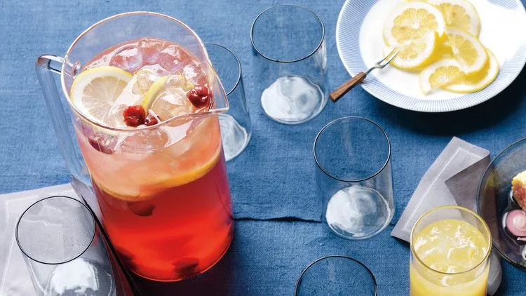A pitcher of Martha Stewart The Firecracker cocktail with sour cherries and rosé, served over ice with lemon slices