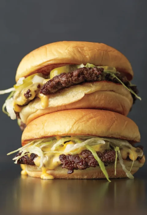 Martha Stewart thin burger with melted American cheese on a toasted potato roll with pickles and lettuce