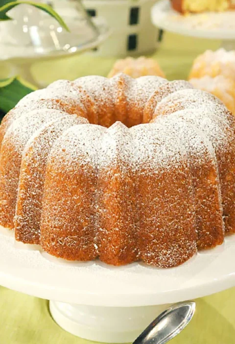 A golden whipped cream cake baked in a Bundt pan, dusted with powdered sugar