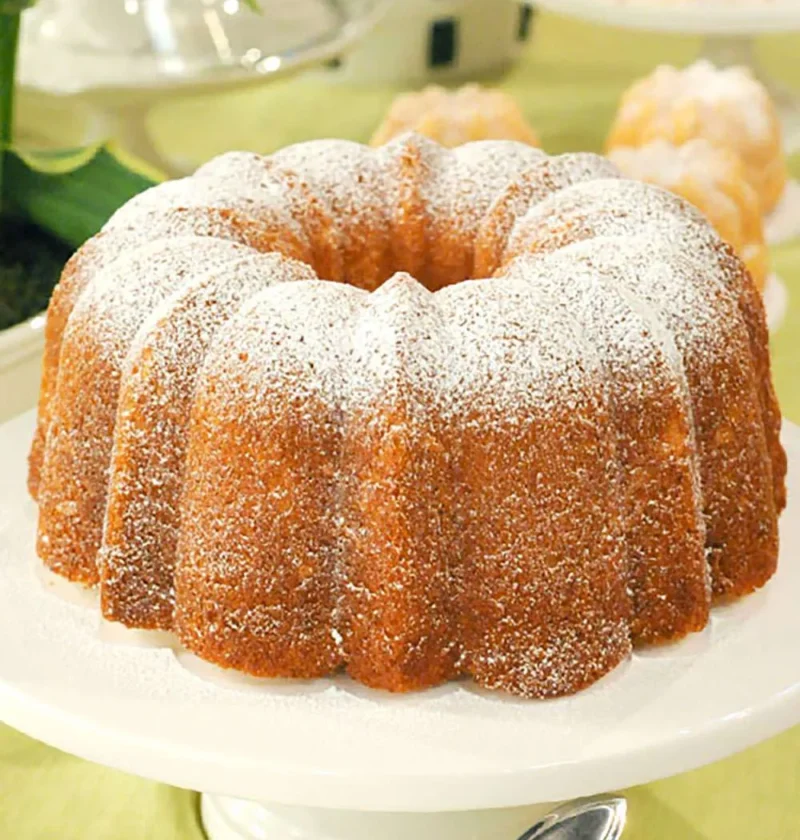 A golden whipped cream cake baked in a Bundt pan, dusted with powdered sugar
