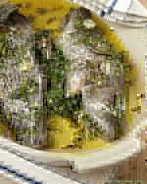 Martha Stewart whole roasted sea bass stuffed with thyme rosemary and bay leaves on a baking dish