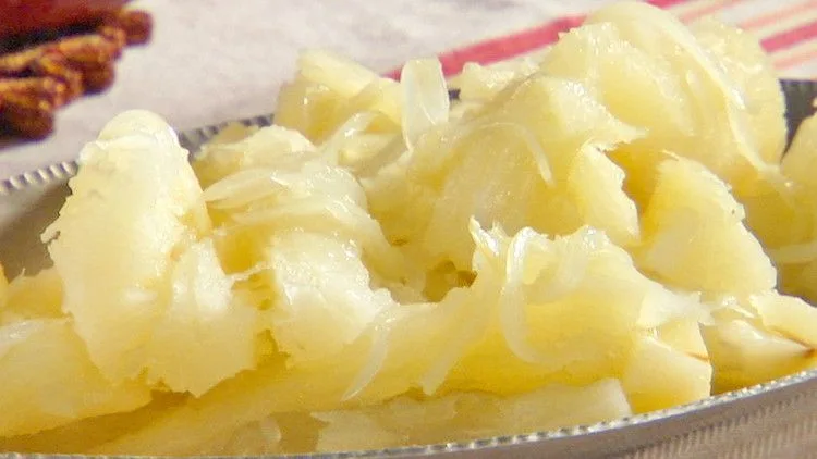 Tender boiled yuca with mojo sauce drizzled over the top on a serving dish