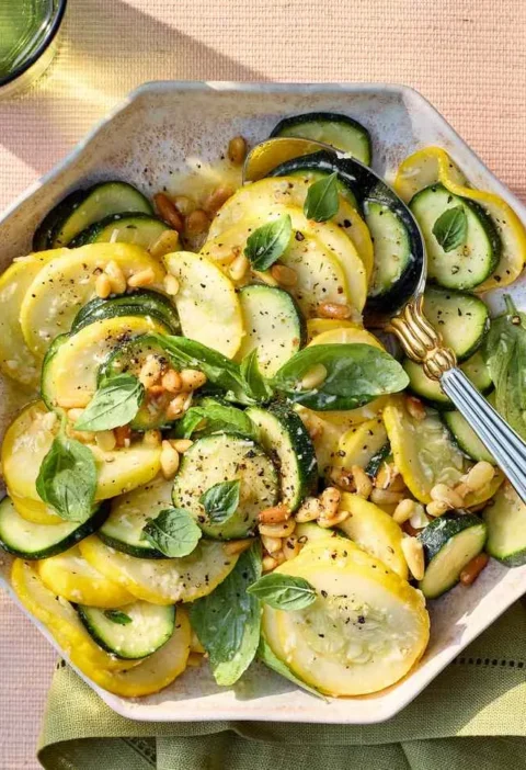 Martha Stewart zucchini and squash salad with pine nuts, Pecorino Romano, and fresh basil on a serving plate