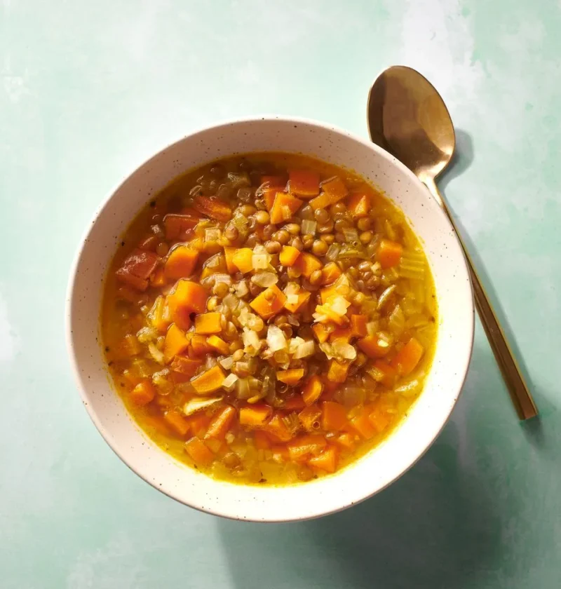 Martha Stewart 15-Minute Lentil Soup with diced carrot, celery and lentils in a speckled bowl with a gold spoon