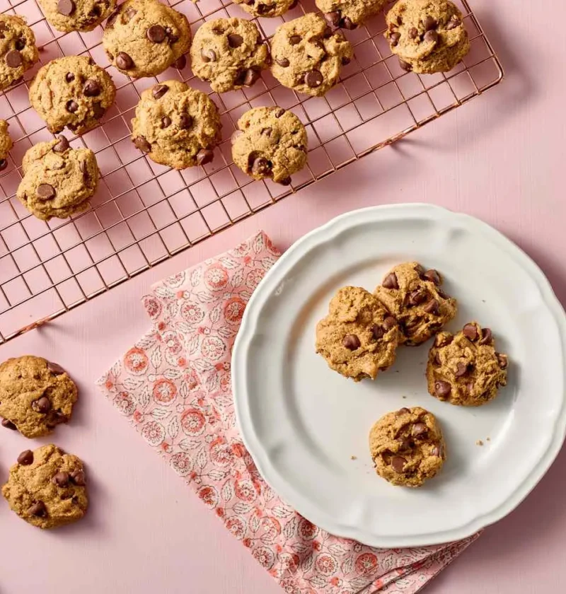 Martha Stewart 5-ingredient chocolate chip cookies cooling on a wire rack and served on a white plate on a pink background