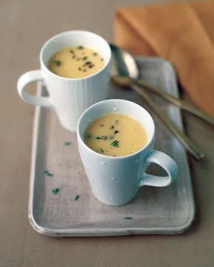 Two white mugs of Martha Stewart acorn squash bisque garnished with fresh thyme on a gray serving tray