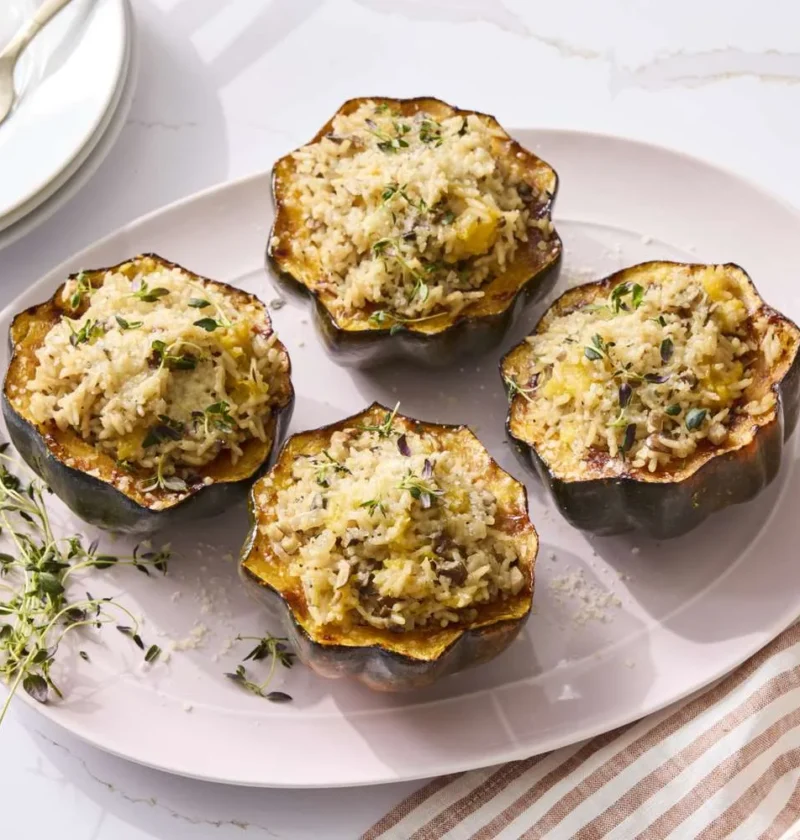Martha Stewart acorn squash stuffed with mushrooms and rice, topped with golden Parmesan and fresh thyme on a white platter