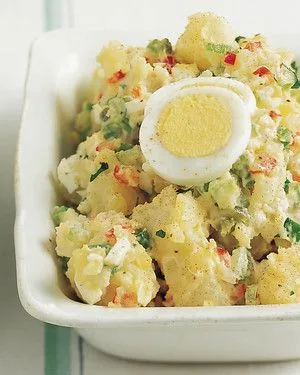 Martha Stewart All-American Potato Salad in a white dish topped with a halved hard-boiled egg and paprika