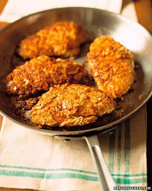 Martha Stewart almond-crusted chicken breasts browned in a stainless steel skillet on a green-striped towel