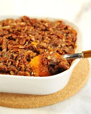 Martha Stewart Amanda Hesser's sweet potato casserole with a pecan brown sugar topping in a white baking dish with a spoon
