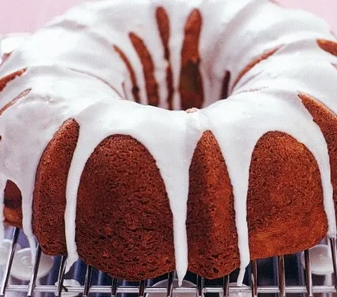 Martha Stewart apple-cinnamon Bundt cake with white glaze dripping down the sides on a wire cooling rack