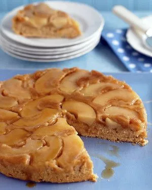 Martha Stewart apple-cinnamon upside-down cake with caramelized apple slices on a blue platter, one slice cut out